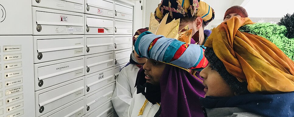 Foto: KJS Salzburg, Pfarre St. Andrä Sternsinger stehen Postkasten und klingeln an Haustüre